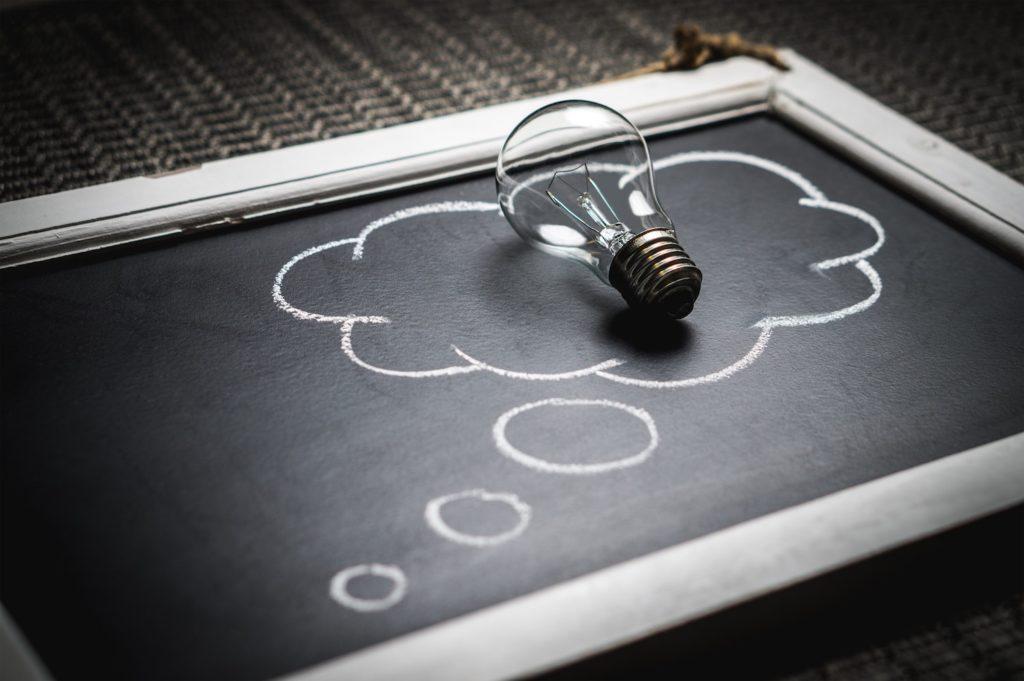 Lightbulb sitting on a chalkboard drawing of a cloud